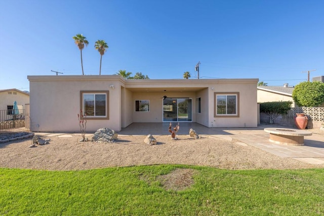 back of property featuring an outdoor fire pit, ceiling fan, a patio area, and a lawn