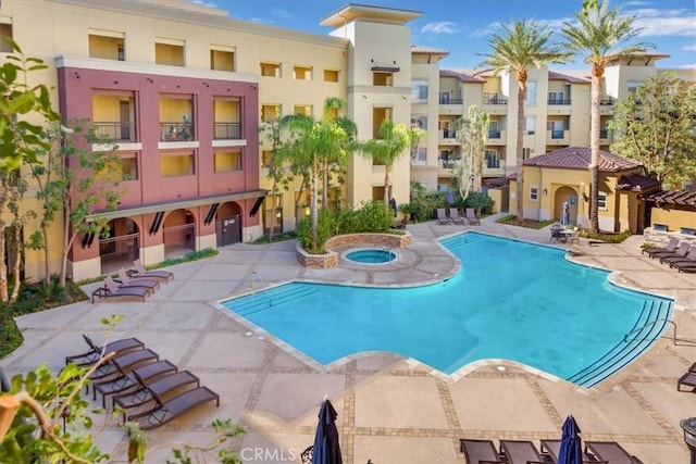 view of pool with a hot tub and a patio