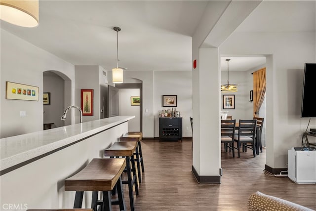 kitchen with light stone countertops, sink, pendant lighting, and dark hardwood / wood-style flooring