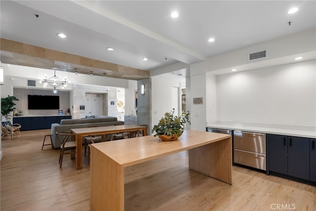 kitchen featuring light wood-type flooring, an inviting chandelier, decorative light fixtures, and a center island