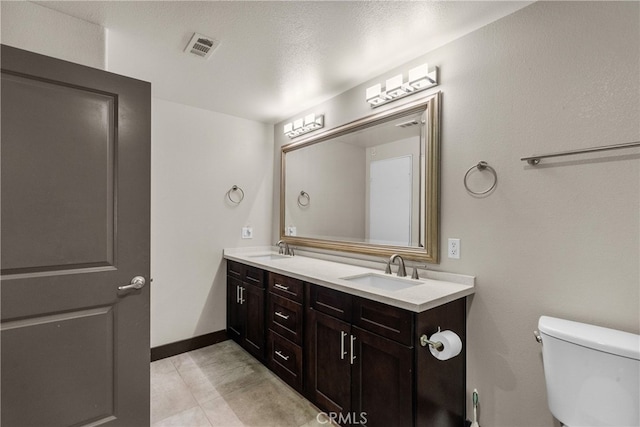 bathroom with toilet, a textured ceiling, tile patterned floors, and vanity