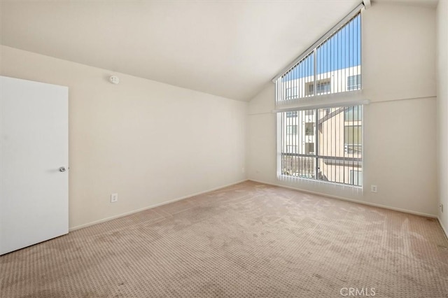 carpeted spare room with high vaulted ceiling