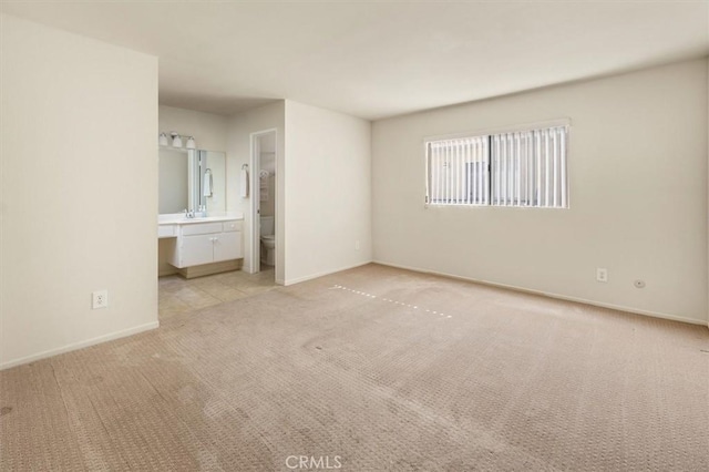 unfurnished bedroom with sink, ensuite bath, and light colored carpet