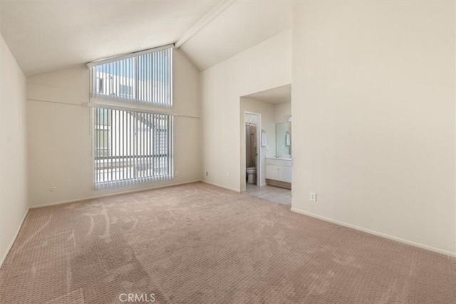 carpeted spare room with beam ceiling and high vaulted ceiling