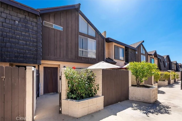 view of front of home featuring fence, a residential view, and stucco siding