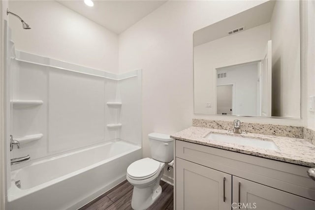 bathroom with visible vents, toilet, wood finished floors, vanity, and shower / washtub combination