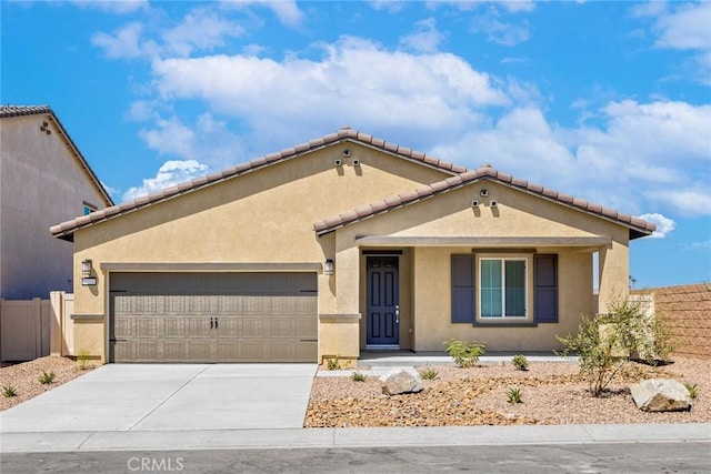 mediterranean / spanish house featuring a garage, concrete driveway, fence, and stucco siding