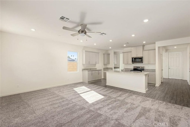 kitchen featuring visible vents, white cabinets, an island with sink, appliances with stainless steel finishes, and open floor plan