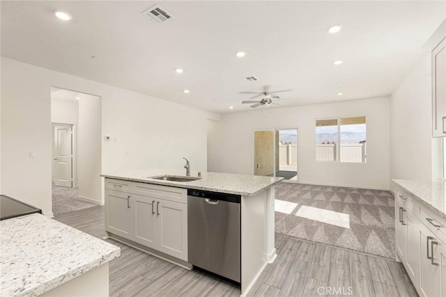 kitchen with white cabinets, light stone countertops, a kitchen island with sink, stainless steel dishwasher, and a sink