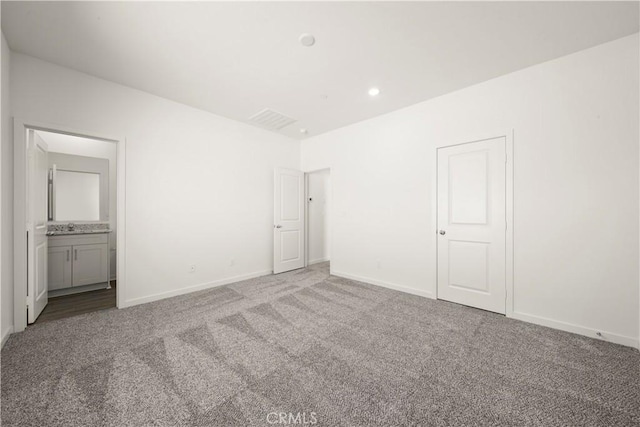 unfurnished bedroom with visible vents, baseboards, connected bathroom, carpet floors, and a sink