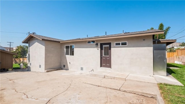 view of front of property with a patio area, fence, and stucco siding