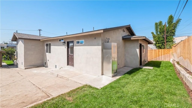 rear view of house featuring fence private yard, a yard, a patio, and stucco siding