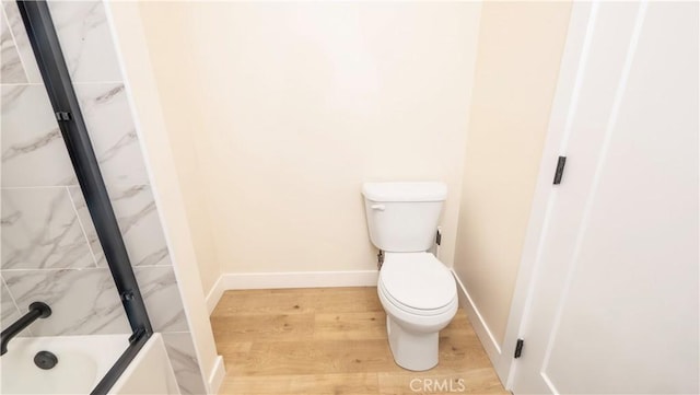 full bathroom with toilet, baseboards, bath / shower combo with glass door, and wood finished floors