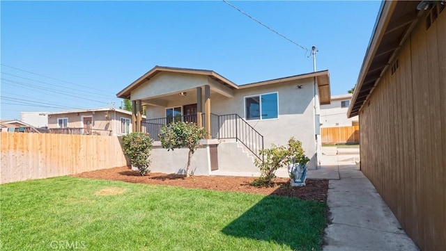 view of front facade featuring a front yard, fence, and stucco siding