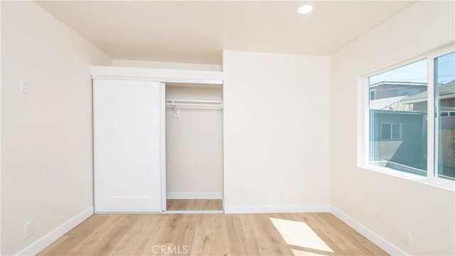 unfurnished bedroom with recessed lighting, a closet, baseboards, and wood finished floors