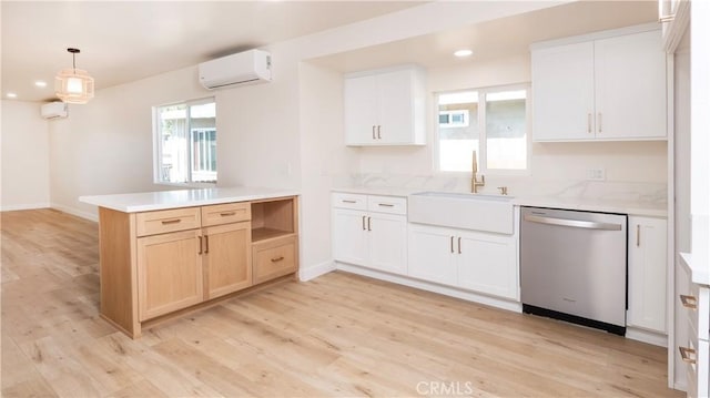 kitchen with a sink, light countertops, stainless steel dishwasher, a wall mounted AC, and light wood-type flooring