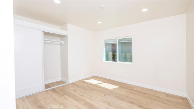 unfurnished bedroom with baseboards, a closet, wood finished floors, and recessed lighting