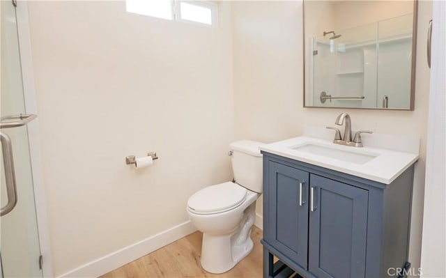 bathroom with baseboards, toilet, wood finished floors, walk in shower, and vanity