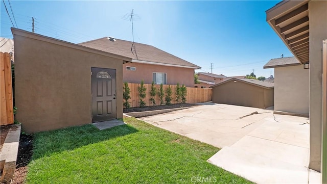 back of house with an outbuilding, a patio area, a fenced backyard, and stucco siding