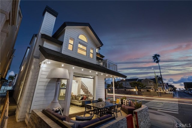 back house at dusk with a balcony