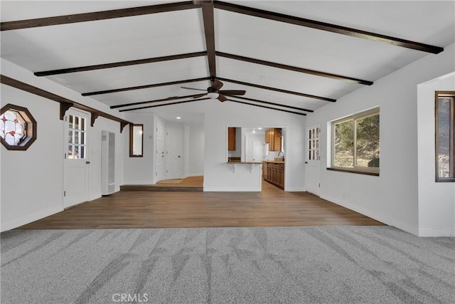 unfurnished living room featuring hardwood / wood-style flooring, ceiling fan, lofted ceiling with beams, and sink