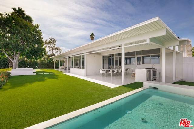 rear view of property featuring a patio and a lawn