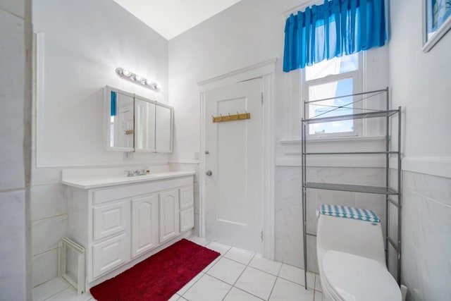 bathroom with tile walls, toilet, vanity, and tile patterned flooring