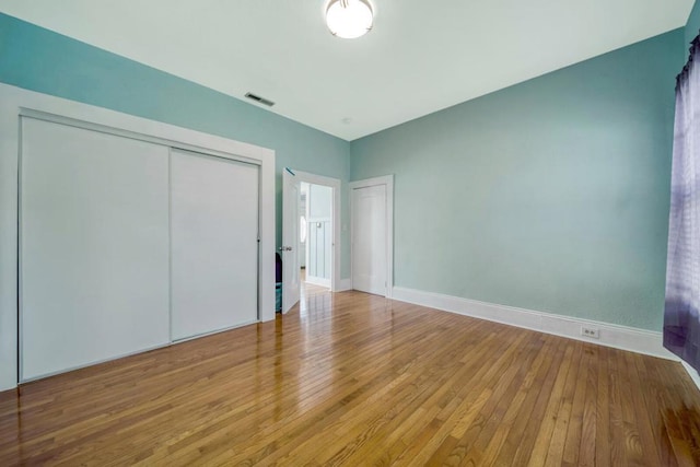 unfurnished bedroom with light wood-type flooring and a closet