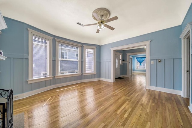 unfurnished living room with light wood-type flooring, ceiling fan, and a healthy amount of sunlight