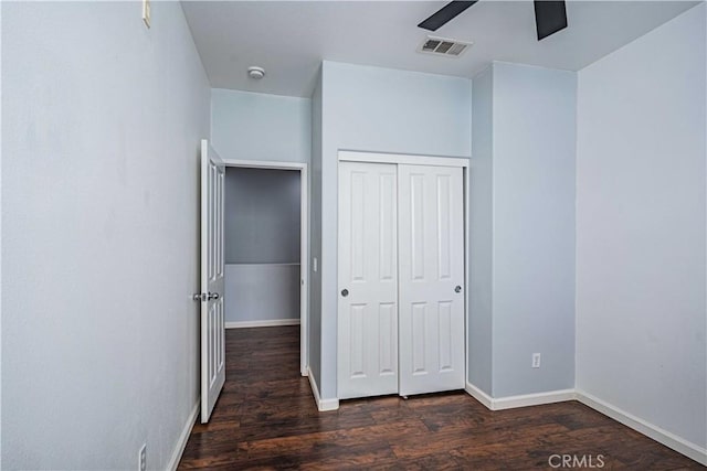 unfurnished bedroom featuring dark hardwood / wood-style flooring, a closet, and ceiling fan