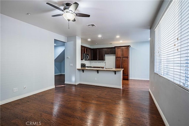 unfurnished living room featuring ceiling fan, dark hardwood / wood-style flooring, and sink