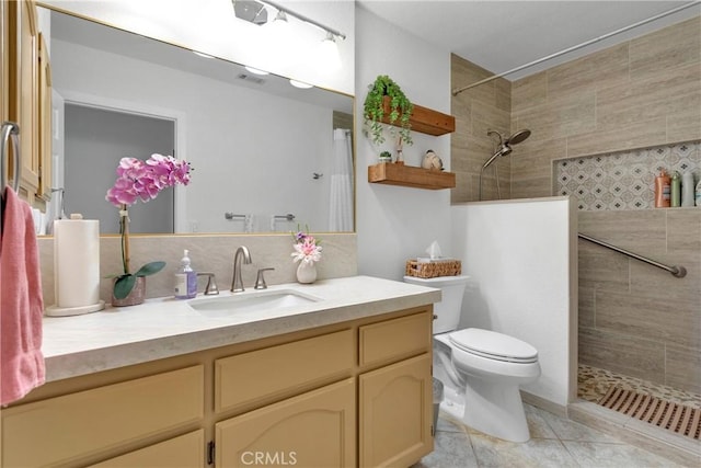 bathroom with a tile shower, tile patterned floors, vanity, and toilet