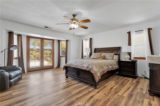 bedroom with access to exterior, ceiling fan, light hardwood / wood-style floors, and a textured ceiling