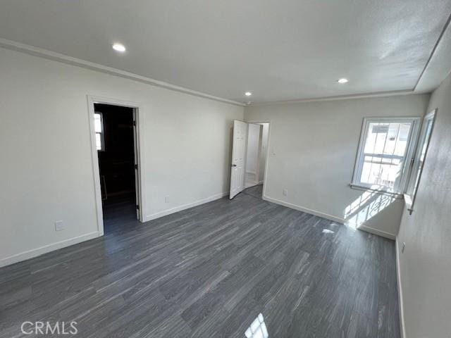 spare room with dark hardwood / wood-style flooring and crown molding