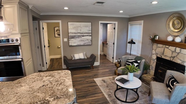 living room featuring crown molding, a stone fireplace, and dark wood-type flooring