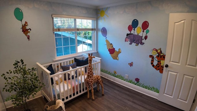 bedroom featuring a nursery area, crown molding, and dark wood-type flooring