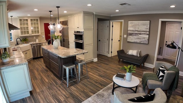 kitchen with dark wood-type flooring, appliances with stainless steel finishes, a kitchen island, pendant lighting, and decorative backsplash