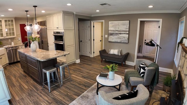 kitchen with appliances with stainless steel finishes, a breakfast bar, tasteful backsplash, hanging light fixtures, and a center island