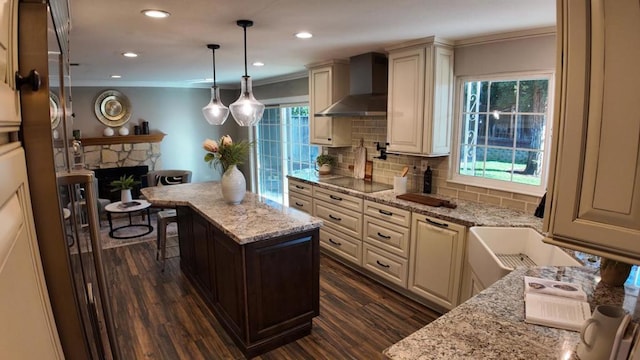 kitchen featuring light stone counters, tasteful backsplash, wall chimney exhaust hood, and a kitchen island