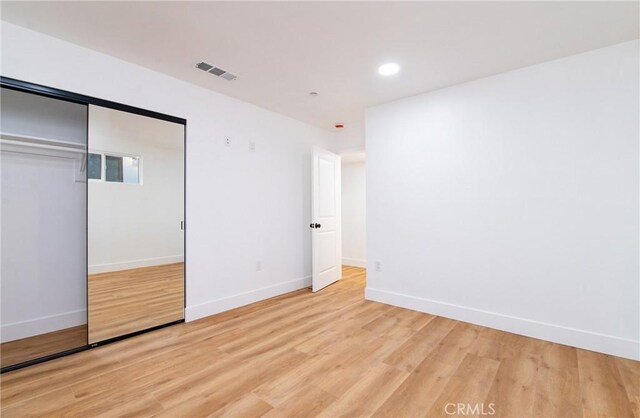 unfurnished bedroom with light wood-type flooring and a closet