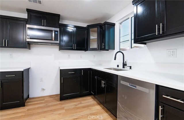 kitchen with sink, stainless steel appliances, and light hardwood / wood-style floors