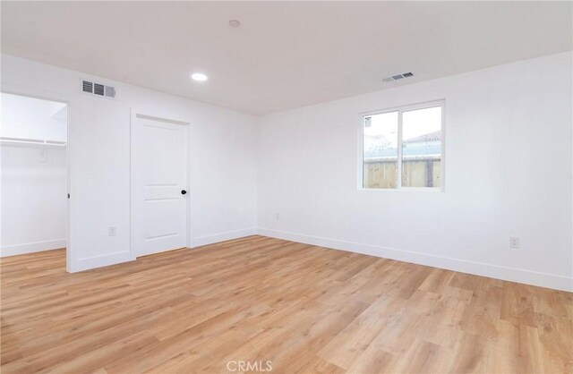 unfurnished bedroom featuring light hardwood / wood-style floors, a spacious closet, and a closet