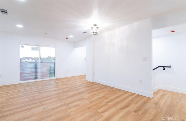 unfurnished room with a chandelier and light hardwood / wood-style flooring