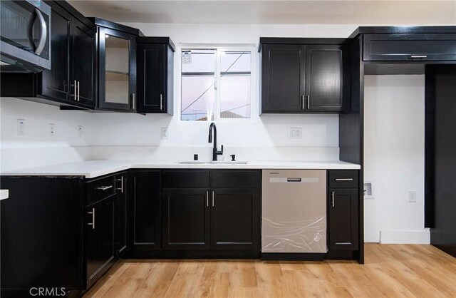 kitchen with sink, appliances with stainless steel finishes, and light hardwood / wood-style flooring