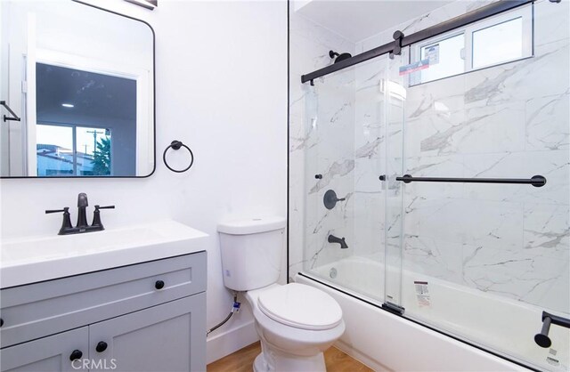 full bathroom featuring hardwood / wood-style floors, vanity, toilet, and shower / bath combination with glass door