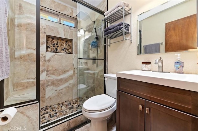 bathroom featuring vanity, toilet, and a shower with shower door