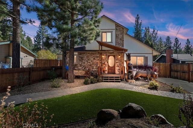 back house at dusk with a lawn and a deck