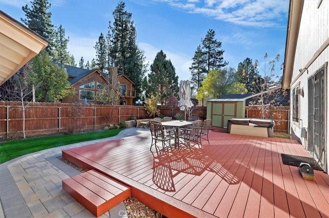 wooden terrace with a covered hot tub and a shed