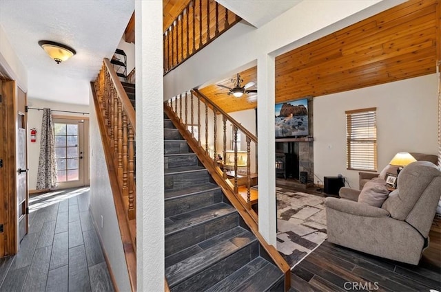 stairway featuring ceiling fan, a fireplace, and wood-type flooring