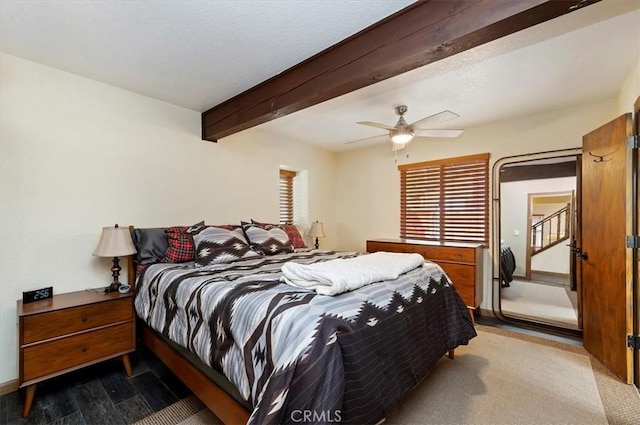 carpeted bedroom with beamed ceiling and ceiling fan